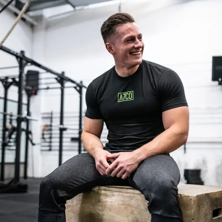 Mike Tennant sitting on a plyo box in the gym, smiling